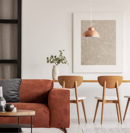 Open plan living and dining room interior with long table with chair and brown velvet settee