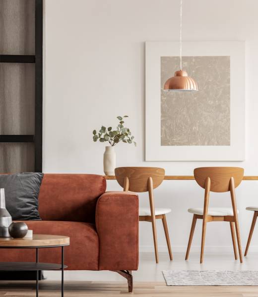 Open plan living and dining room interior with long table with chair and brown velvet settee